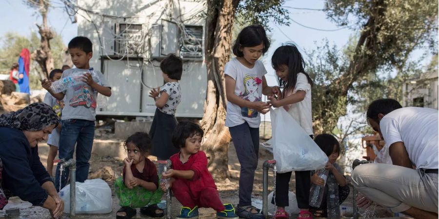 Flüchtlinge waschen sich an einer Wasserstelle in einem provisorischen Lager nahe dem Flüchtlingslager Moria.