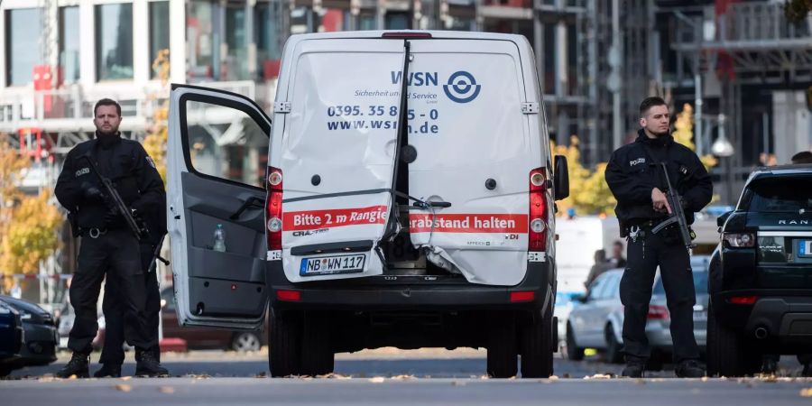 Mehrere Polizisten mit Maschinenpistolen sichern in Berlin den Geldtransporter mit aufgebrochenen Türen in Mitte.