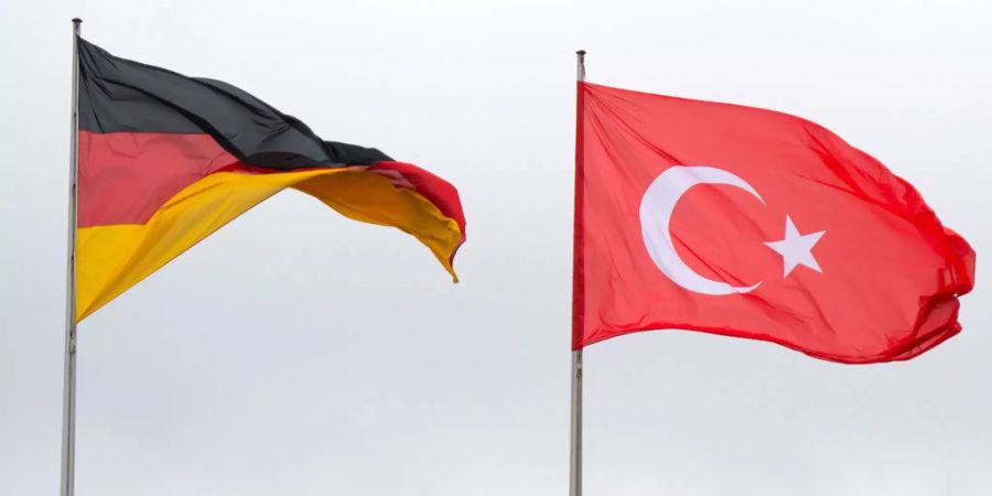 Eine deutsche und eine türkische Fahne im Wind.