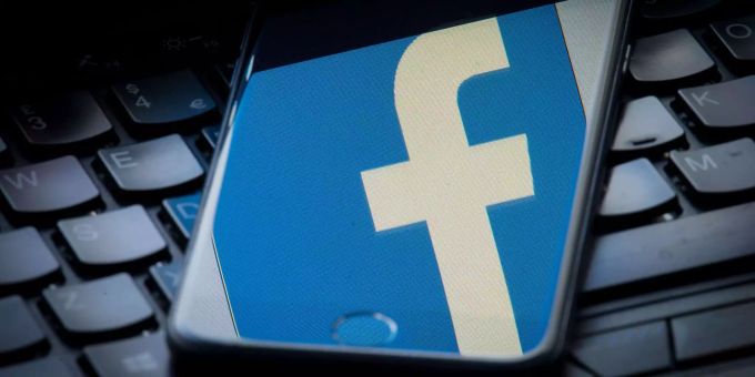 Das Facebook-Logo wird auf einem Smartphone gespiegelt, das auf einer Tastatur liegt. Facebook