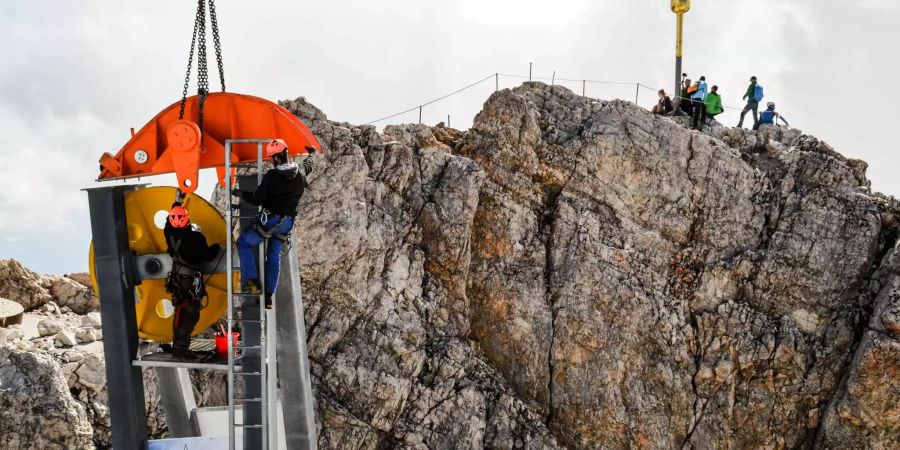 Bauarbeiter demontieren Teile der Materialseilbahn zwischen Zugspitzgipfel und Gipfelterrasse.
