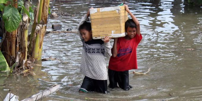 Kinder in einem philippinischen Dorf bringen ihre Habseligkeiten vor dem Taifun «Yutu» in Sicherheit. Kinder waten mit einer geschulterten Kiste im Wasser