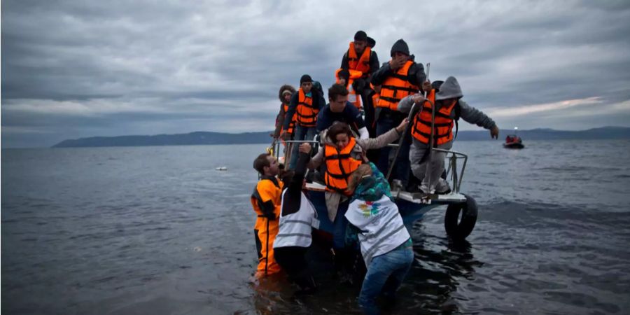 Freiwillige helfen Flüchtlinge aus einem Boot.