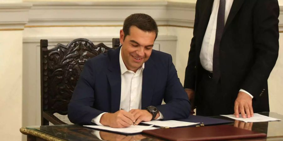 Der griechische Regierungschef Alexis Tsipras unterzeichnet ein Protokoll.