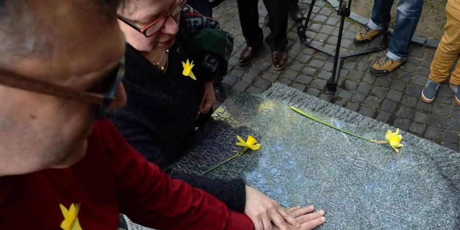 Ein Mann berührt anlässlich des 75. Jahrestages zum Aufstand im Warschauer Ghetto ein Denkmal.