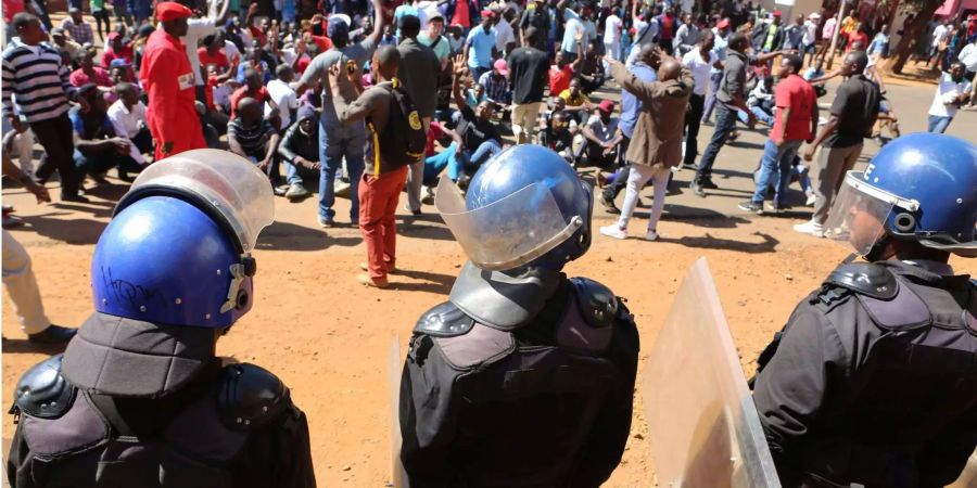 Polizisten halten Anhänger der Oppositionspartei MDC davon ab, in das Hauptquartier der Wahlkommission einzudringen.