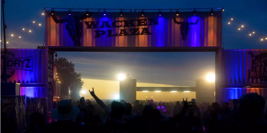 Staub zieht abends über das Festivalgelände des Open-Airs in Wacken (D).