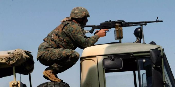 Ein georgischer Soldat hockt auf einem Lastwagen und zielt mit seinem Maschinengewehr während einer Militärübung. Ein georgischer Soldat hockt auf einem Lastwagen und zielt mit seinem Maschinengewehr während einer Militärübung.