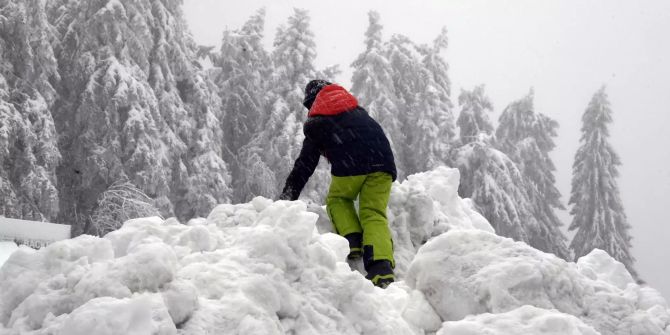 Ein Kind klettert auf einen Schneehügel.