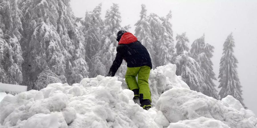 Ein Kind klettert auf einen Schneehügel.