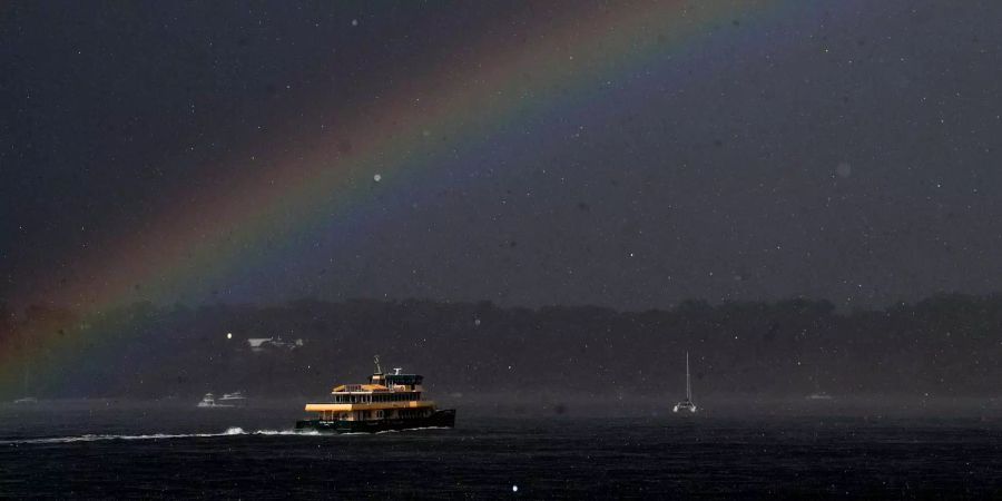 Eine Fähre fährt während des Sturms unter einem Regenbogen.