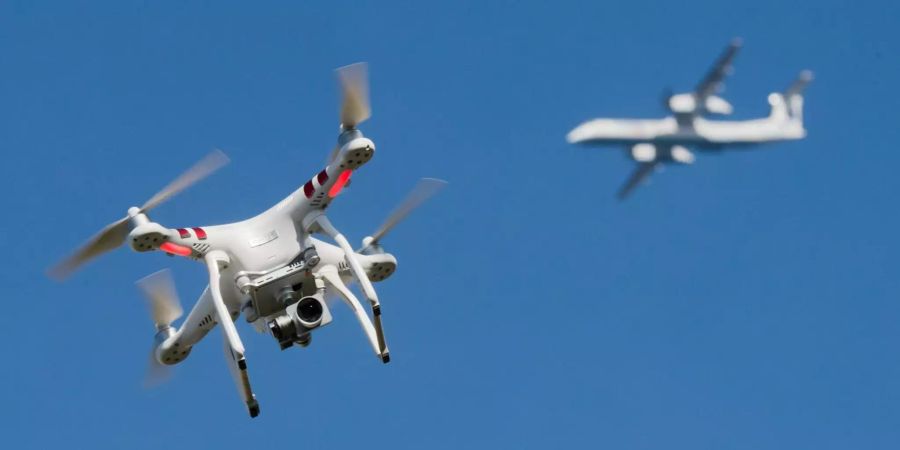 Eine private Drohne fliegt in in weiter Entfernung von einem Flugzeug.