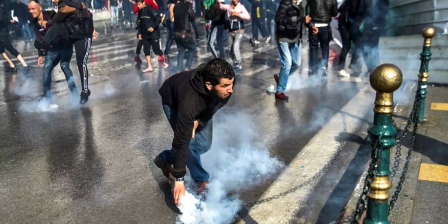 Ein Demonstrant hebt einen Behälter mit Tränengas auf