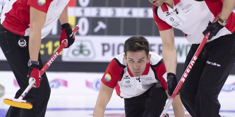 Schweizer Teamwork in Kanada: Peter De Cruz bei der Steinabgabe, Valentin Tanner (links) und Sven Michel in Wischbereitschaft