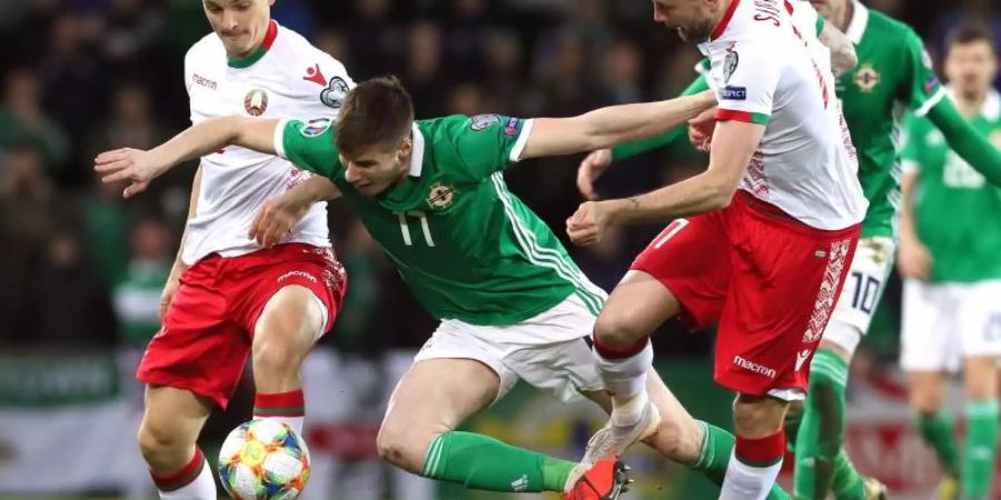 Der Nordire Paddy McNair (M) wird von zwei Weissrussen zu Fall gebracht. Foto: Brian Lawless/PA Wire