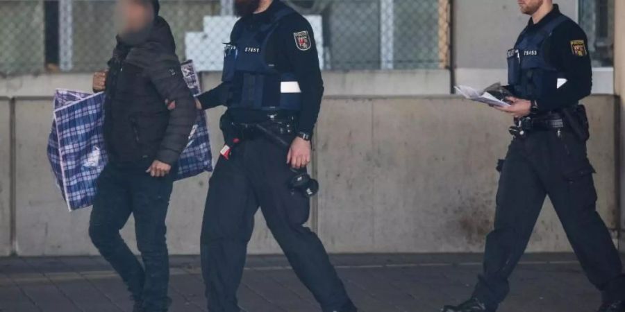 Polizisten begleiten einen Mann (l) in ein Terminal des Flughafens, von wo aus er mit einer gecharterten Maschine am Abend nach Afghanistan abgeschoben werden soll. Foto: Boris Roessler
