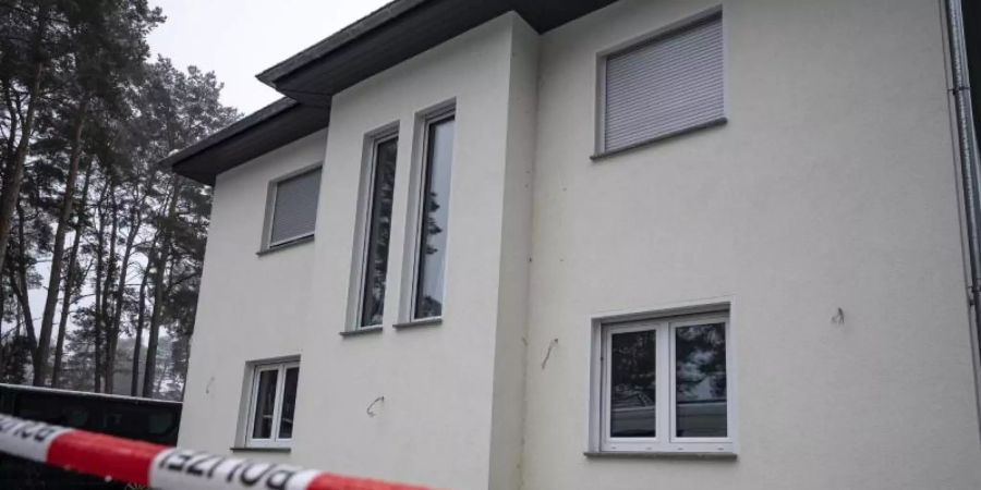 Das Einfamilienhaus in Senzig, einem Ortsteil der Stadt Königs Wusterhausen im Landkreis Dahme-Spreewald, ist abgesperrt. Die Polizei hat dort fünf Tote in einem Wohnhaus gefunden. Foto: Fabian Sommer/dpa