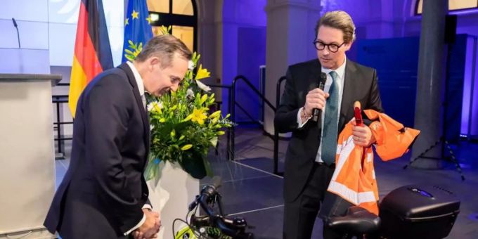 Volker Wissing (FDP, l), Bundesminister für Verkehr und Digitales, nimmt von Andreas Scheuer (CSU), scheidender Bundesminister für Verkehr und digitale Infrastruktur, bei der Amtsübergabe im Bundesministerium für Verkehr und Digitales einen Fahrradhelm und weitere Ausrüstung entgegen. Foto: Christoph Soeder/dpa