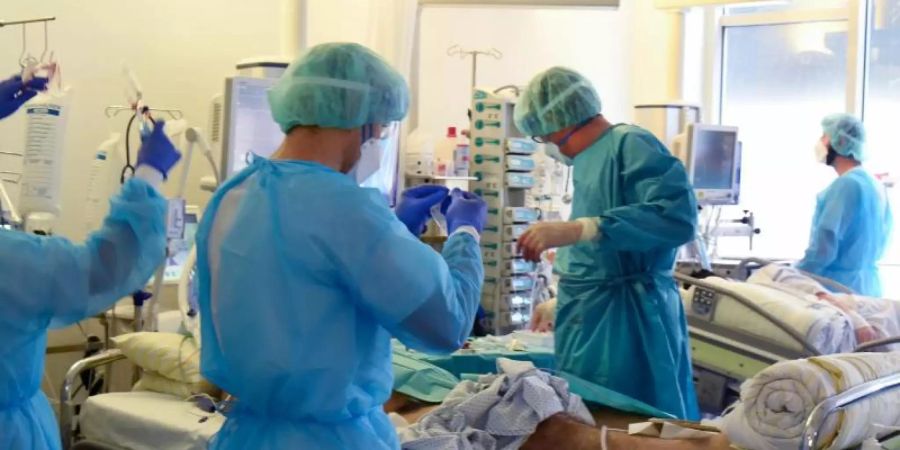 Auf der Covid-Station vom Universitätsklinikum Leipzig versorgen Ärzte, Schwestern und Pfleger einen Patienten. Foto: Waltraud Grubitzsch/dpa-Zentralbild/dpa