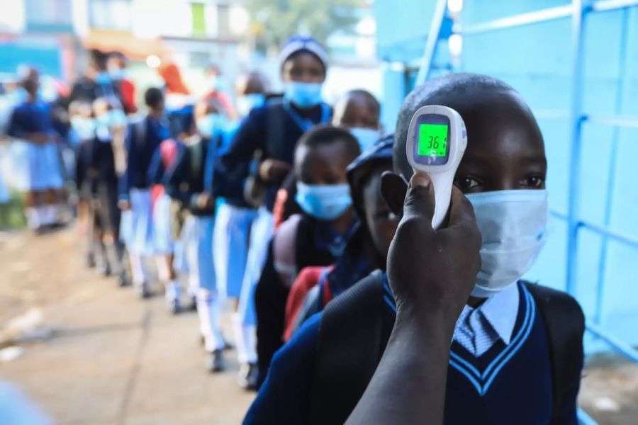 Schülern in Nairobi, Kenia, wird auf dem Weg zu ihren Klassenzimmern die Temperatur gemessen.