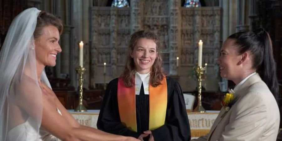 Vikarin Rebecca (Antonia Bill, m.) traut zwei Frauen (Emma Skinner und Rachel Leigh, l-r) in einer Szene von "Rosamunde Pilcher: Im siebten Himmel". Foto: Jon Ailes/ZDF/dpa