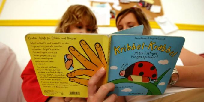 Erzieherin liest einem Kita-Kind vor Erzieherin liest einem Kita-Kind vor