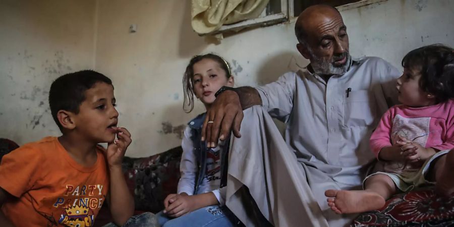 Der Lebensmittelverkäufer Khaled Amash spricht mit seinen Kindern in seinem neuen Haus. Das alte Haus von Amash wurde nach einem Bombenangriff durch regimetreue Kräfte zerstört. Foto: Anas Alkharboutli/dpa