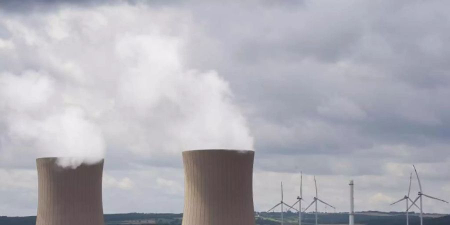 Dampf steigt aus den Kühltürmen eines Atomkraftwerks. Im Hintergrund sind Windräder zu sehen. Foto: Julian Stratenschulte/dpa