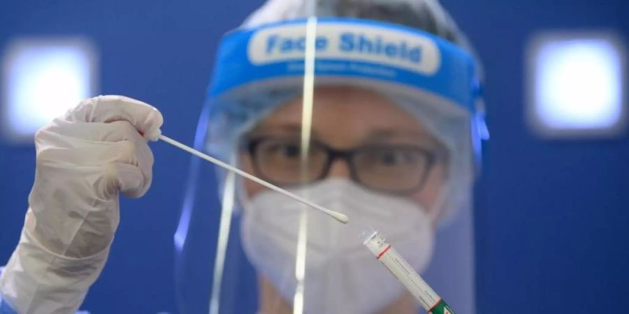 Eine Ärztin der Kassenärztlichen Vereinigung Sachsen hält in der Corona-Teststation für Urlaubsrückkehrer am Flughafen Dresden International einen Coronavirus-Test in den Händen. Foto: Robert Michael/dpa-Zentralbild/dpa