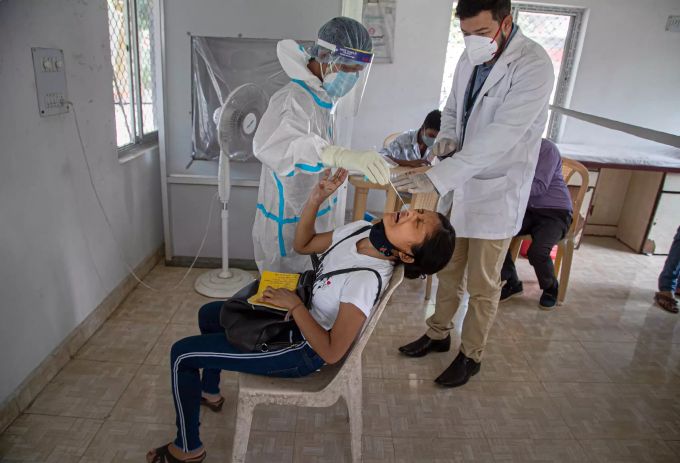 Ein Mitarbeiter des indischen Gesundheitswesens nimmt eine Nasenabstrichprobe bei einem Mädchen. Indien Coronavirus test mädchen