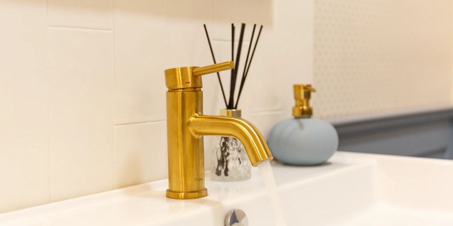Goldfarbene Details verleihen dem grauen Bad einen Hauch von Luxus.