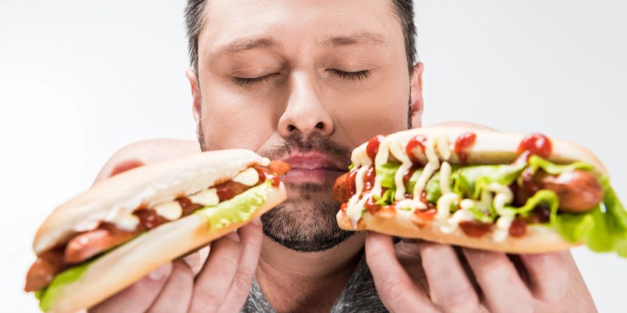 Mann riecht an zwei Hotdogs