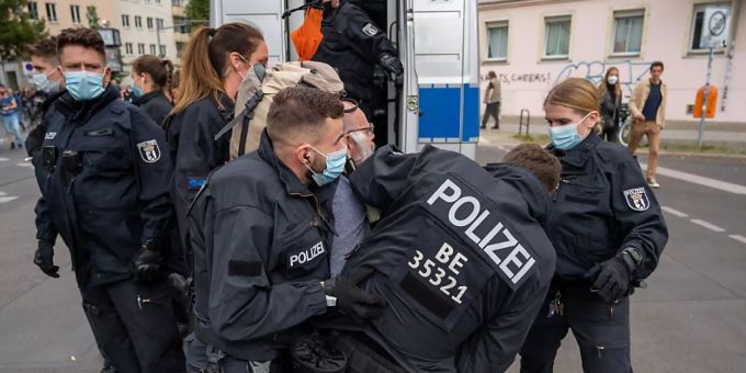 Polizisten halten an einem Polizeiwagen einen Teilnehmer der Demonstration fest, die aus Protest gegen die Corona-Politik veranstaltet wird. Foto: Christophe Gateau/dpa Polizisten halten an einem Polizeiwagen einen Teilnehmer der Demonstration fest, die aus Protest gegen die Corona-Politik veranstaltet wird. Foto: Christophe Gateau/dpa