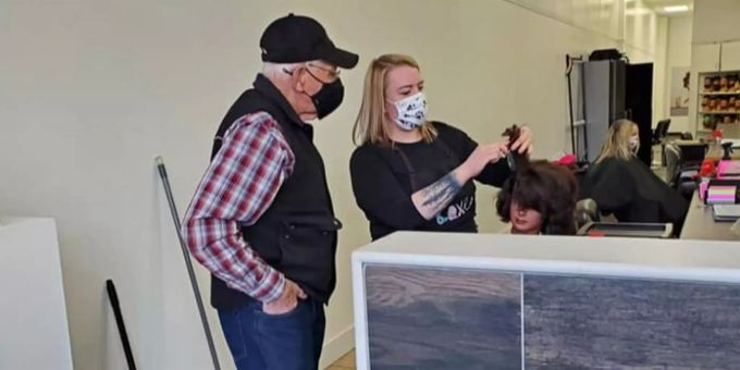 Eine fortgeschrittene Kosmetikschülerin in Red Deer zeigt einem 79-jährigen kanadischen Rentner anhand einer Puppe, wie man mit einem Lockenstab umgeht. Good News Rentner Kosmetik
