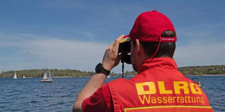 Ein Mitglied der Deutschen Lebensrettungs-Gesellschaft (DLRG) beobachtet die Boote auf dem Wannsee. Foto: Paul Zinken/dpa