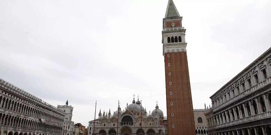 ARCHIV - Ein Mann geht über den leeren Markusplatz in Venedig - Touristen bleiben auch hier vorerst aus. Foto: Antonio Calanni/AP/dpa