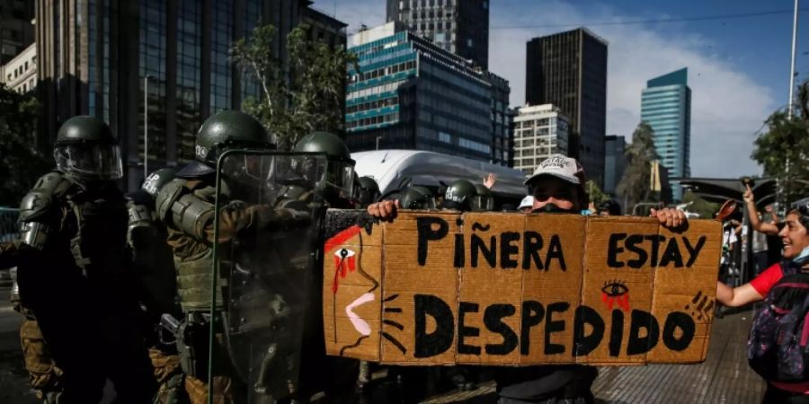 Ein Demonstrant hält ein Banner mit der Aufschrift: «Piñera raus»