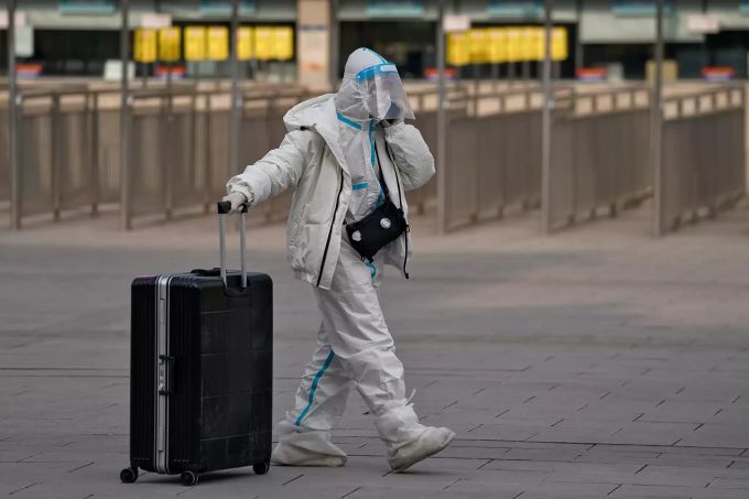 Eine Frau begibt sich in China in Schutzkleidung an den Bahnhof. china corona