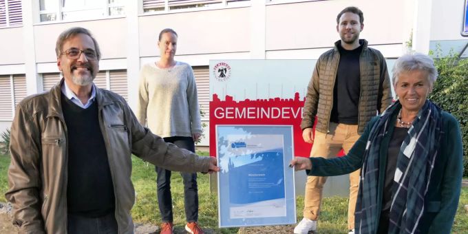 Gemeindepräsidentin Jeanne Locher-Polier (vorne rechts) und Departementsvorsteher Raum & Umwelt Daniel Altermatt präsentieren die neue Energiestadt-Urkunde. Im Hintergrund Sandra Thomann und Benjamin Kobler, Mitarbeitende der Bauverwaltung und Mitglieder der Arbeitsgruppe Energiestadt Münchenstein.