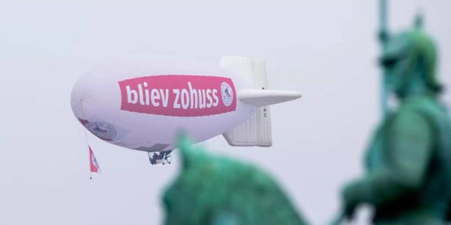 Ein Zeppelin mit der Aufschrift «bliev zohuss» (Bleib zu Hause) der Roten Funken hinter dem Reiterdenkmal in Köln. Foto: Rolf Vennenbernd/dpa