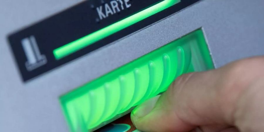 Eine Bankkundin steckt ihre Girokarte in einen Geldautomaten. Bankkunden müssen für ihr Girokonto mehr zahlen. (Symbolbild). Foto: Fabian Sommer/dpa