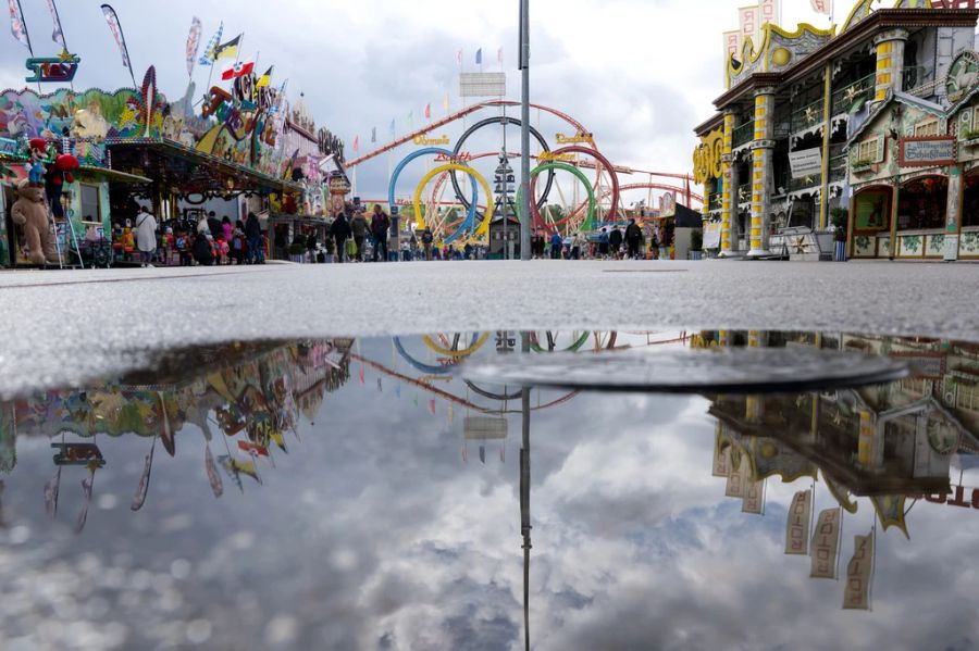 Die Olympia-Achterbahn spiegelt sich auf dem Oktoberfest in einer Pfütze.