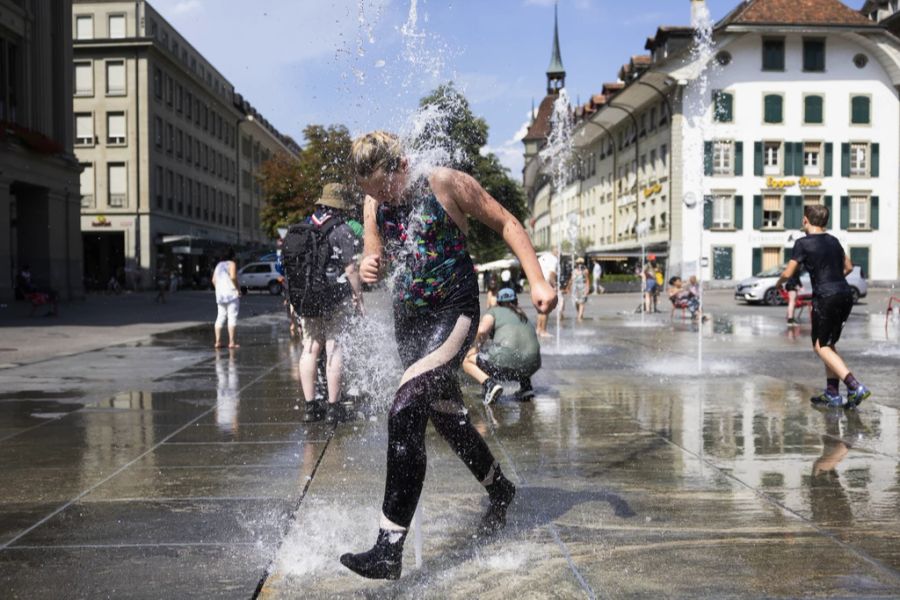 Eine Pfadfindergruppe erfrischt sich bei den Wasserstrahlen auf dem Bundesplatz.