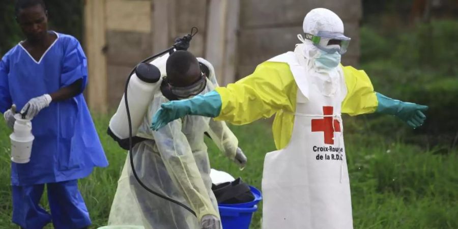 Helfer reinigen sich nach der Arbeit in einem Behandlungszentrum gegen Ebola mit Desinfektionsmittel. Im Kongo sind inzwischen mehr als 2000 Menschen an dem gefährlichen Ebola-Virus erkrankt. Foto: Al-Hadji Kudra Maliro/AP