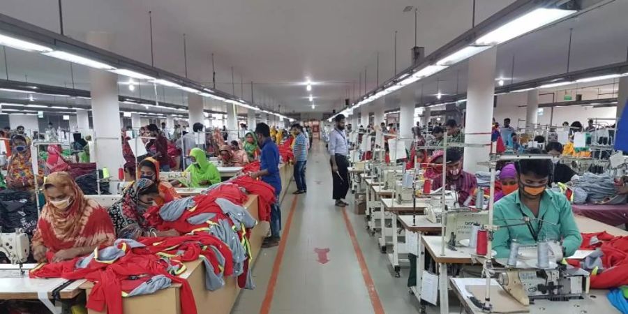 In einer Textilfabrik im bangladeschischen Savar sitzen Näherinnen und Näher bei der Arbeit. Foto: Nick Kaiser