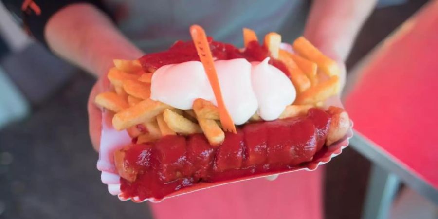 Lazo Vujinovic steht anlässlich des 70. Geburtstags der Currywurst vor Curry 36 mit einer Currywurst und Pommes. Foto: Jörg Carstensen