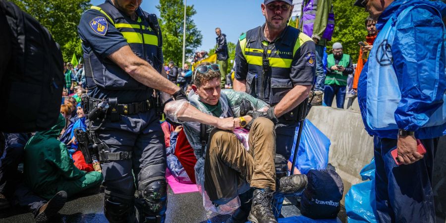 Die Polizei trägt Aktivisten von Extinction Rebellion weg, die die  A12 in Den Haag blockieren.