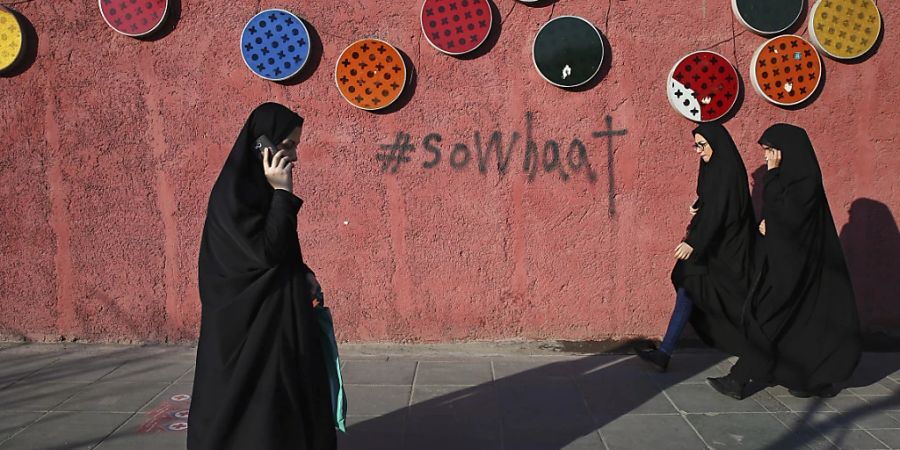 ARCHIV - Eine mit Tschador und Hidschab gekleidete Frau läuft telefonierend durch die Strassen. (Symbolbild) Foto: Ebrahim Noroozi/AP/dpa