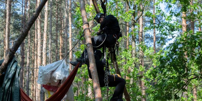 Ein Aktivist wird von einem Polizeibeamten aus einem Baumhaus in der Wuhlheide geholt. Ein Aktivist wird von einem Polizeibeamten aus einem Baumhaus in der Wuhlheide geholt.