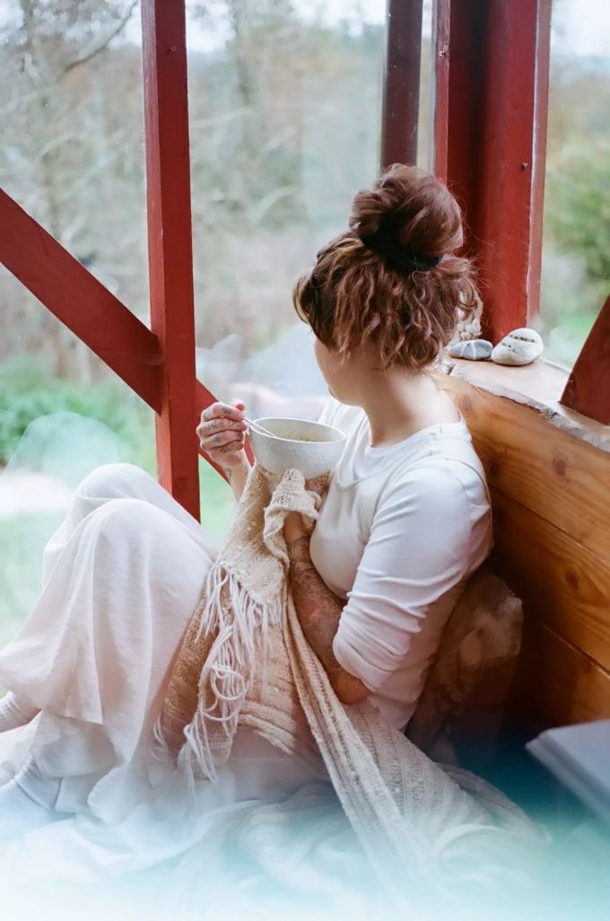 Trinken Sie Ihren morgendlichen Kaffee einmal ganz bewusst, ohne Ablenkung. Frau sitzt am Fenster.